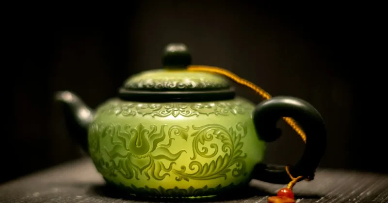 A decorative green teapot with ornate carvings